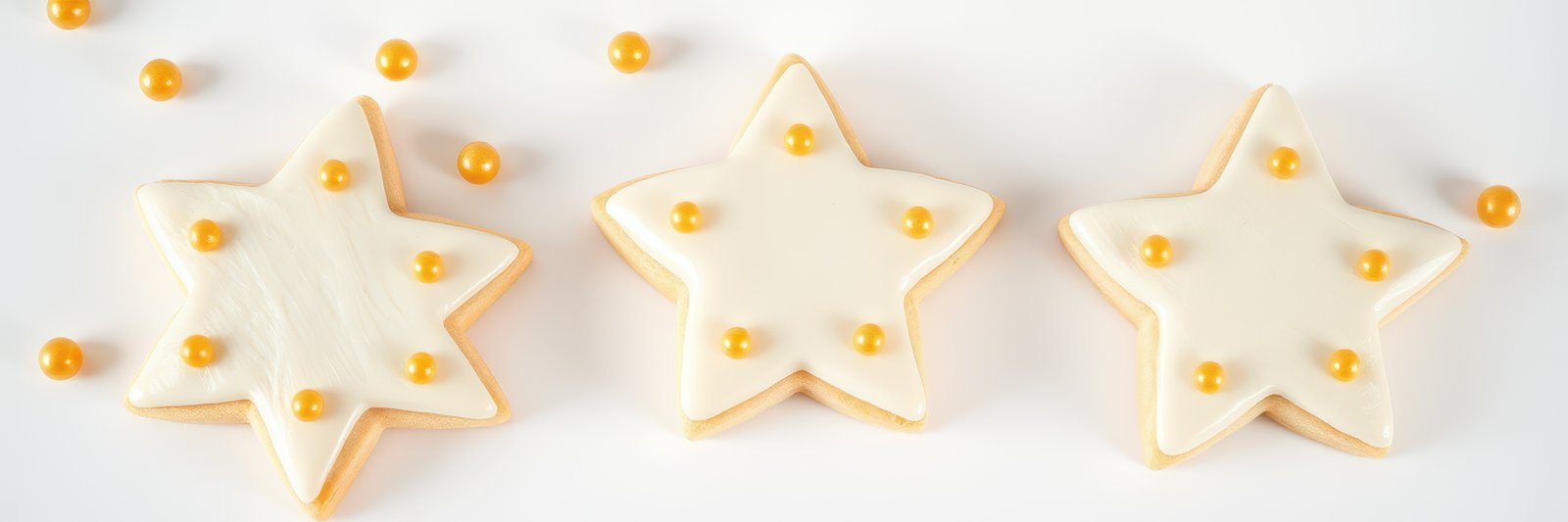 Decorated star-shaped cookies with yellow accents arranged on a white background for a festive occasion